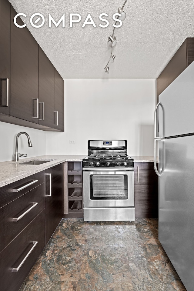 kitchen featuring stainless steel appliances, a sink, dark brown cabinets, modern cabinets, and a textured ceiling