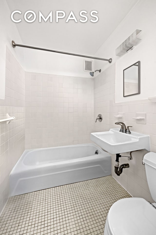 bathroom featuring tile walls, toilet, tile patterned flooring, shower / tub combination, and a sink