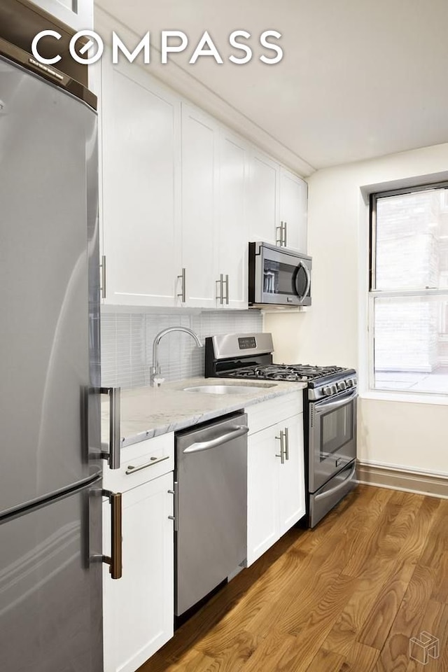 156-08 Riverside Dr W Unit 1K, New York City, NY 10032 - kitchen featuring stainless steel appliances, wood finished floors, white cabinets, and light stone countertops