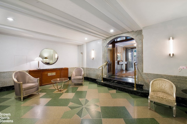 building lobby with a wainscoted wall, beamed ceiling, and recessed lighting