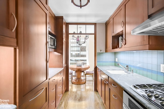 kitchen featuring under cabinet range hood, stainless steel appliances, a sink, and decorative backsplash