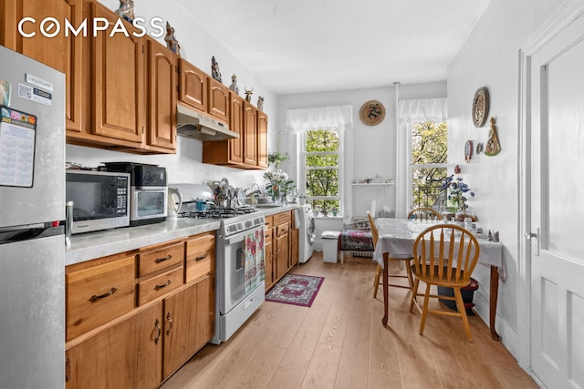 139 N 8th St, New York City, NY 11249 - kitchen featuring stainless steel appliances, under cabinet range hood, light wood-style floors, light countertops, and brown cabinetry