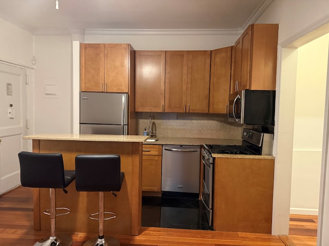 57 W 58th St Unit 3H, New York City, NY 10019 - kitchen with stainless steel appliances, brown cabinets, a breakfast bar, ornamental molding, and dark wood-type flooring