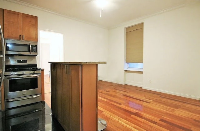 57 W 58th St Unit 3H, New York City, NY 10019 - kitchen featuring appliances with stainless steel finishes, crown molding, wood finished floors, brown cabinetry, and a center island
