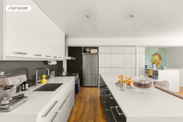 kitchen featuring appliances with stainless steel finishes, a sink, modern cabinets, tasteful backsplash, and white cabinets