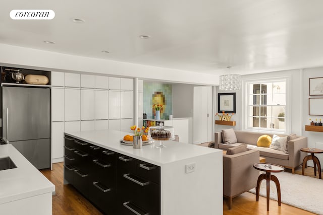 kitchen featuring dark cabinets, freestanding refrigerator, light countertops, dark wood finished floors, and open floor plan