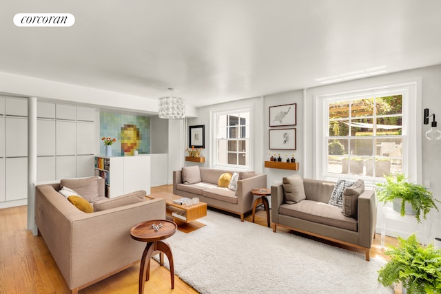 living area featuring light wood-style flooring and a chandelier
