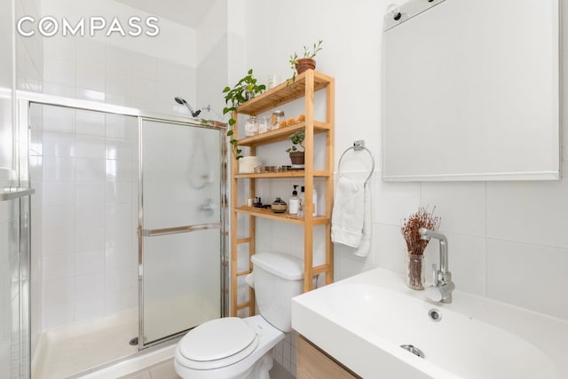 bathroom with a stall shower, toilet, and a sink