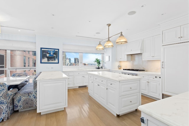 415 E 54th St Unit 25Gg, New York City, NY 10022 - kitchen with a kitchen island, premium range hood, ornamental molding, light wood-style floors, and white cabinetry