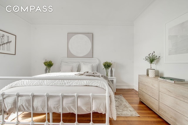 bedroom with light wood-style floors, ornamental molding, and baseboards