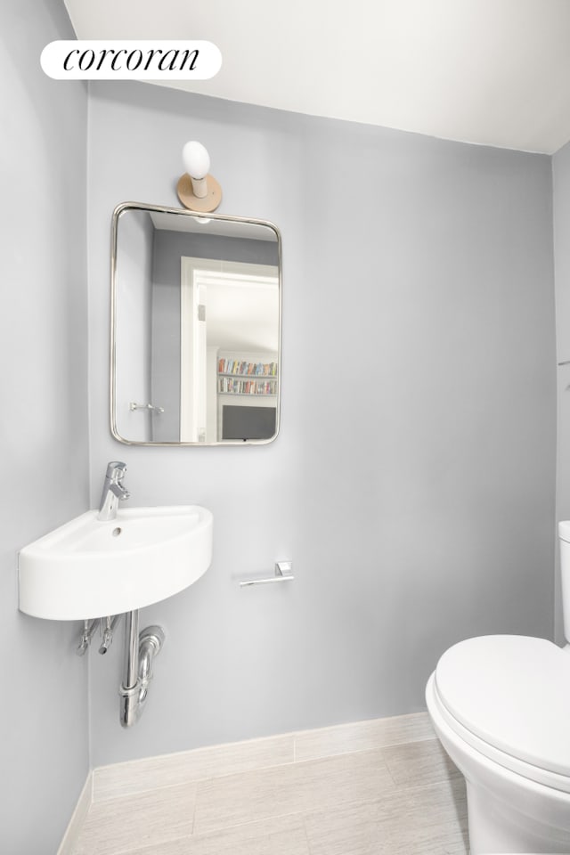 half bath featuring toilet and baseboards