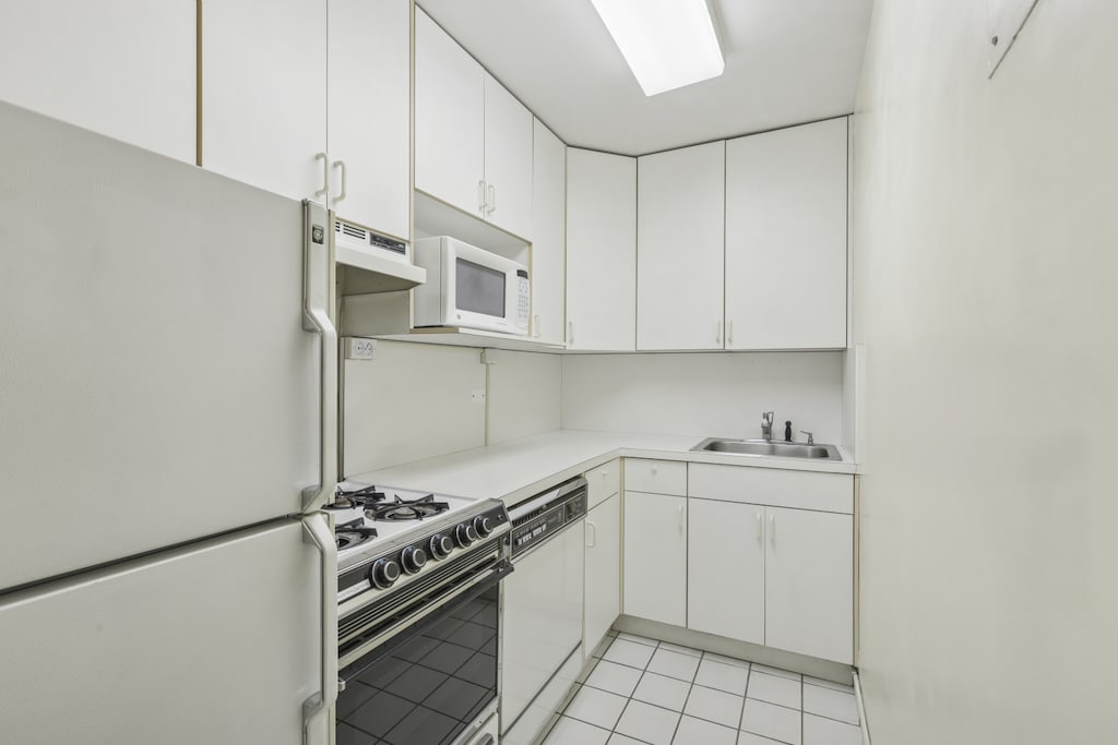 kitchen featuring white appliances, a sink, white cabinetry, and light countertops
