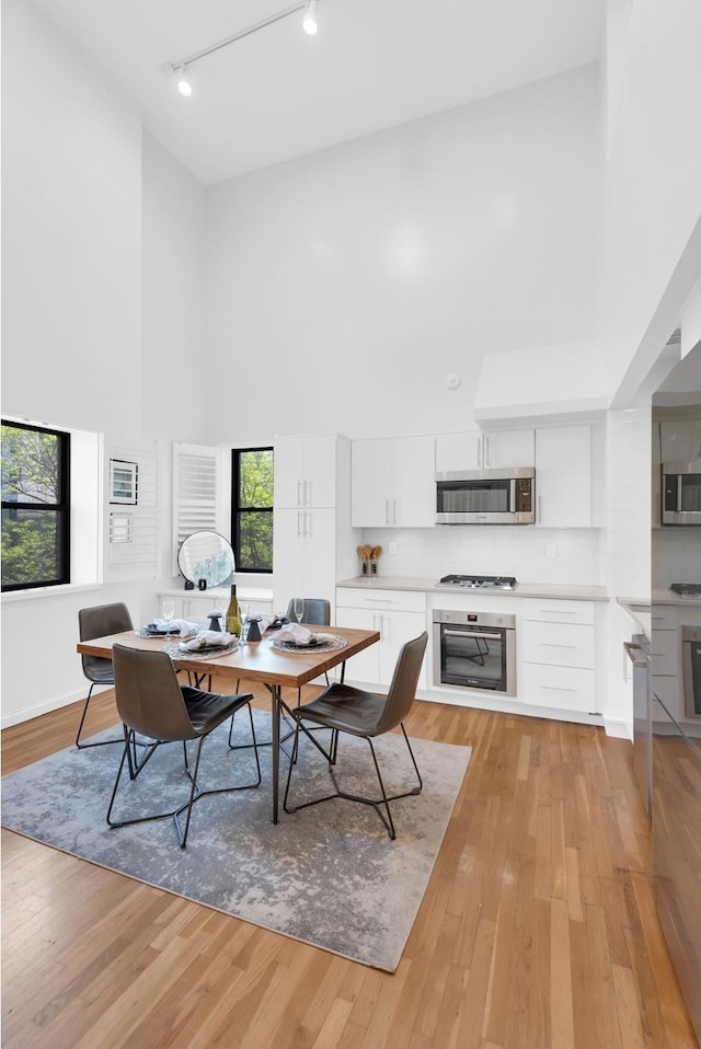 office space featuring a high ceiling, rail lighting, and light wood-type flooring