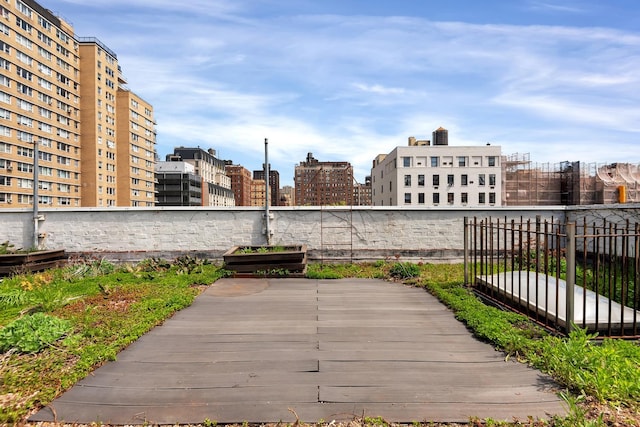 wooden terrace featuring fence and a view of city