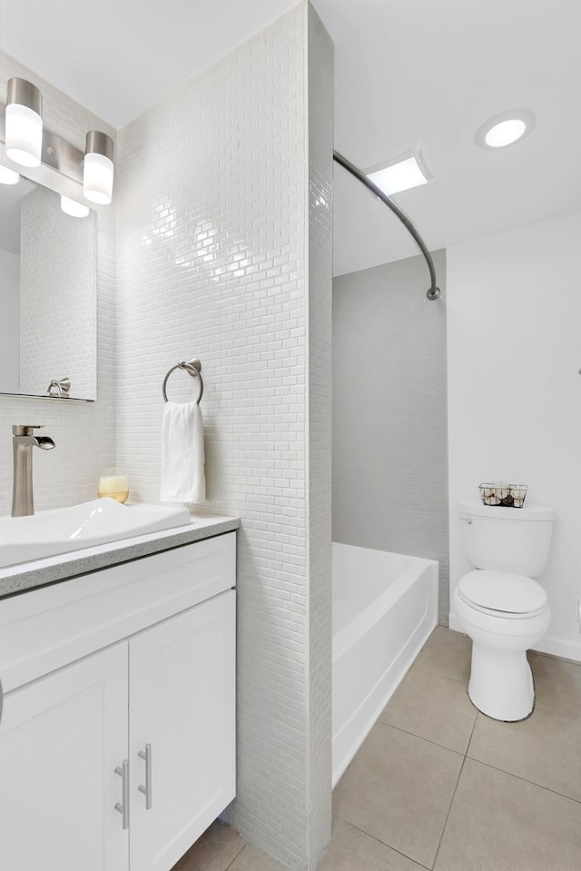 bathroom featuring tile patterned floors, tile walls, toilet, vanity, and  shower combination