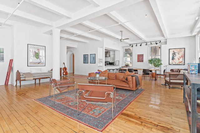 living room featuring arched walkways, hardwood / wood-style flooring, beamed ceiling, and a ceiling fan