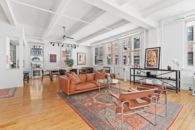living area with beam ceiling, ceiling fan, and wood-type flooring