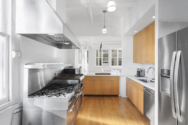 kitchen with appliances with stainless steel finishes, a sink, extractor fan, light wood-type flooring, and light countertops