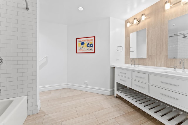 bathroom featuring double vanity, shower / washtub combination, and baseboards