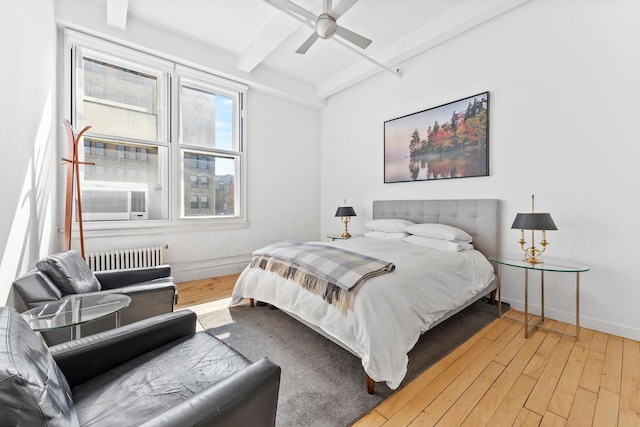 bedroom featuring beamed ceiling, radiator, wood-type flooring, baseboards, and ceiling fan