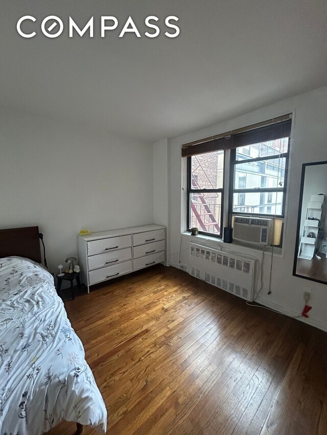 bedroom with radiator, hardwood / wood-style flooring, and cooling unit