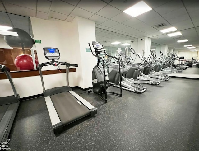 workout area featuring a drop ceiling and baseboards