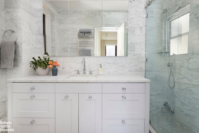 full bathroom featuring a marble finish shower and vanity
