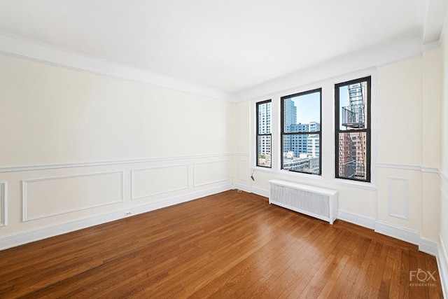 255 W End Ave Unit 12C, New York City, NY 10023 - spare room with radiator heating unit, hardwood / wood-style flooring, a decorative wall, and wainscoting