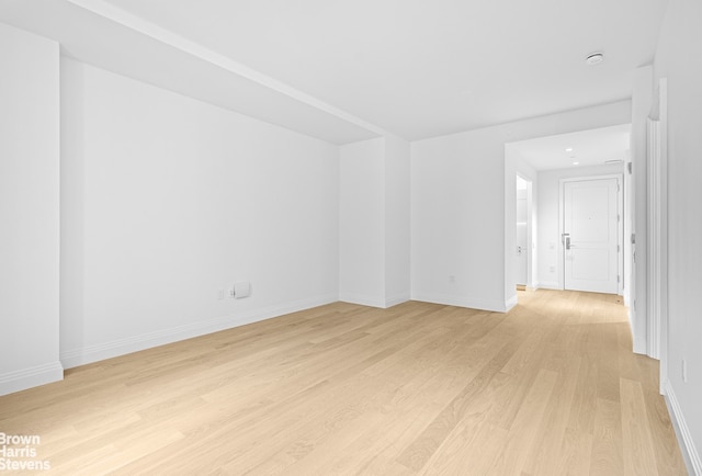 empty room featuring light wood finished floors and baseboards