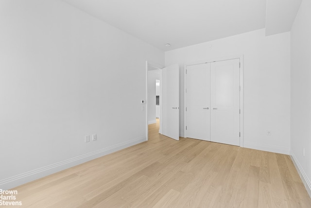 unfurnished bedroom with light wood finished floors, baseboards, and a closet