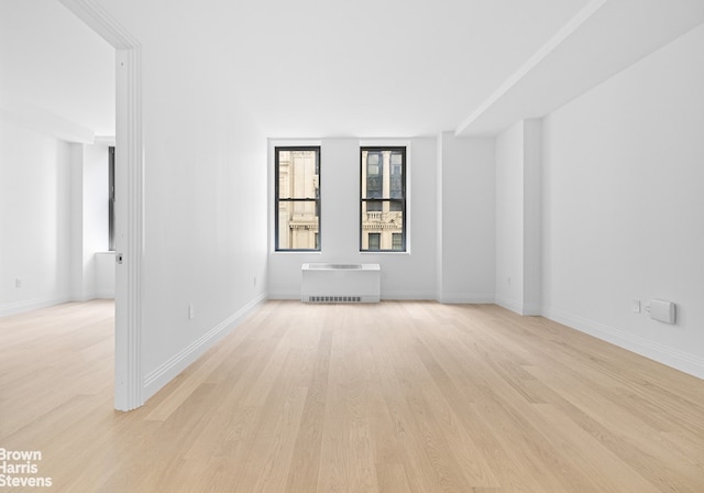 unfurnished room featuring light wood-style flooring, heating unit, and baseboards