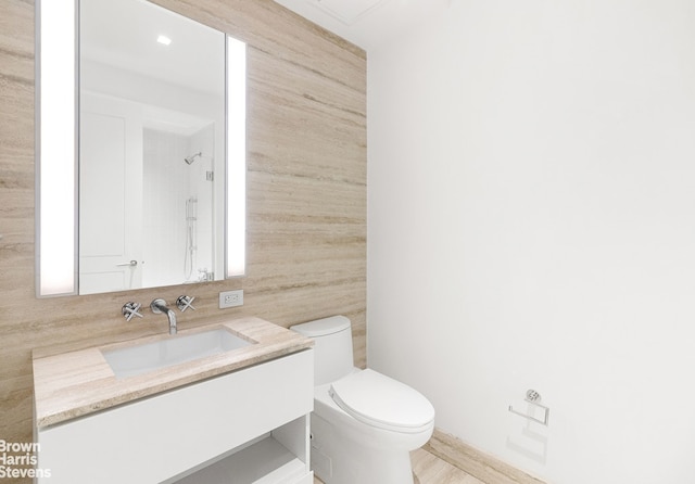 bathroom featuring tile walls, toilet, vanity, and a shower