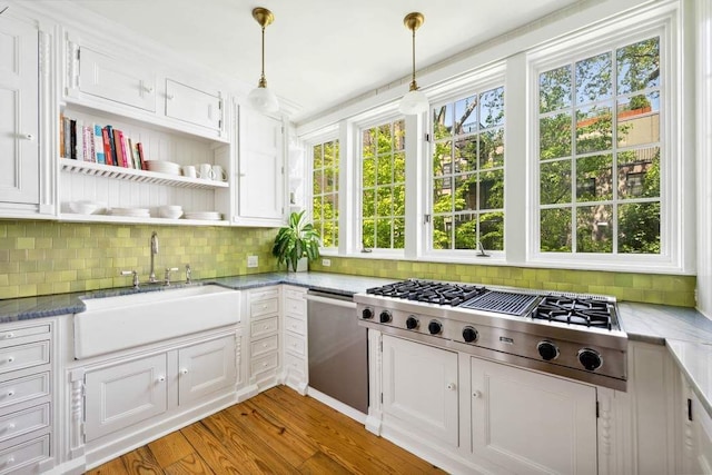 149 E 18th St Unit 2, New York City, NY 10003 - kitchen with a sink, stainless steel appliances, decorative backsplash, white cabinetry, and pendant lighting