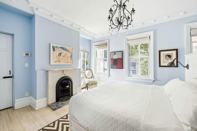 149 E 18th St Unit 2, New York City, NY 10003 - bedroom featuring crown molding, light wood-style floors, a chandelier, baseboards, and a premium fireplace