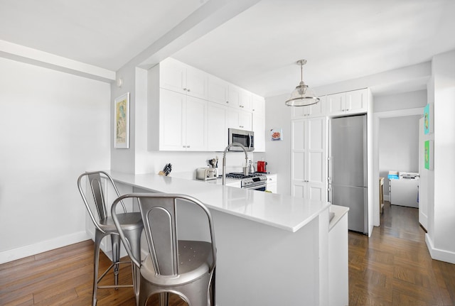 755 W End Ave Unit 15C, New York City, NY 10025 - kitchen with appliances with stainless steel finishes, baseboards, a peninsula, a kitchen bar, and light countertops