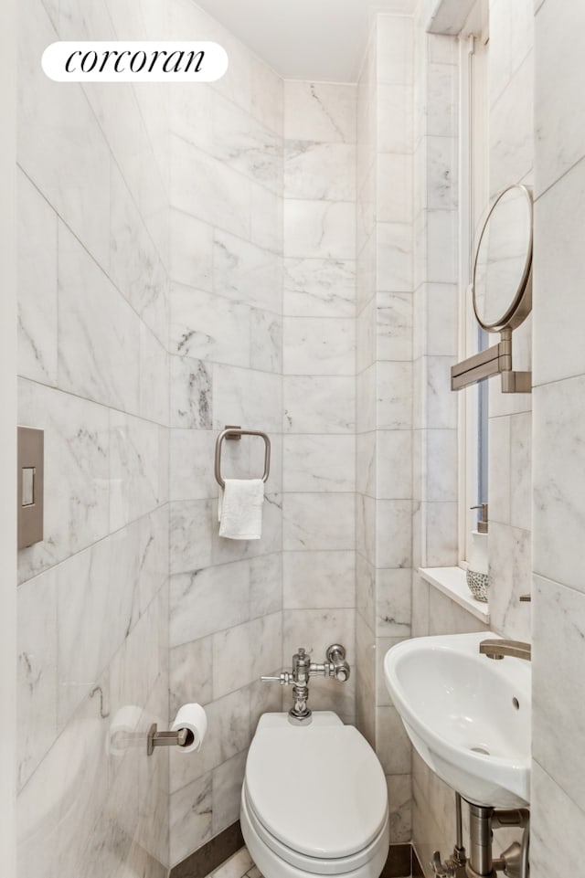 half bath with a sink, tile walls, and toilet