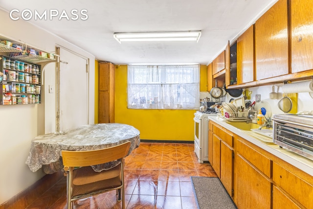 1274 Herkimer St, New York City, NY 11233 - kitchen featuring gas range gas stove, light countertops, light tile patterned floors, and brown cabinetry