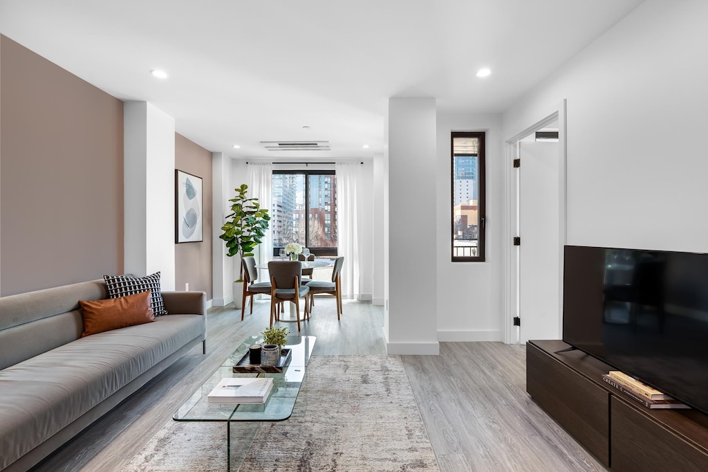 living room featuring light wood-style flooring, baseboards, and recessed lighting