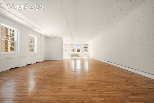 unfurnished living room featuring hardwood / wood-style flooring and a textured wall
