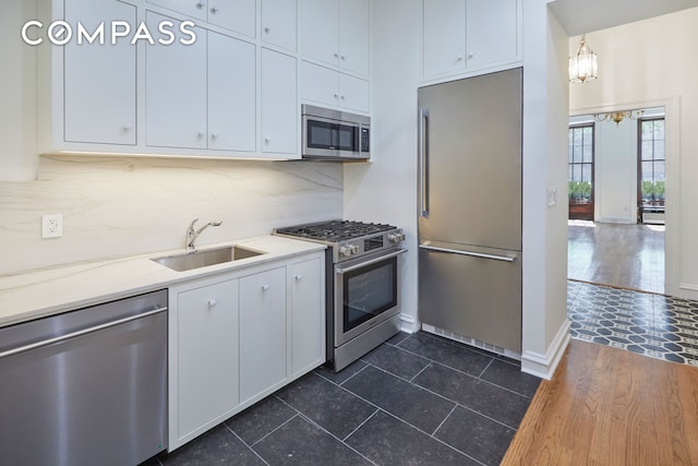 157 E 75th St Unit 1E, New York City, NY 10021 - kitchen with stainless steel appliances, a sink, white cabinets, tasteful backsplash, and light countertops