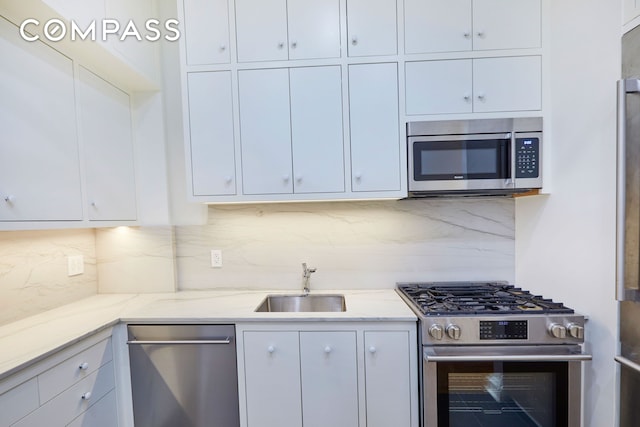157 E 75th St Unit 1E, New York City, NY 10021 - kitchen with stainless steel appliances, a sink, white cabinets, and light stone countertops