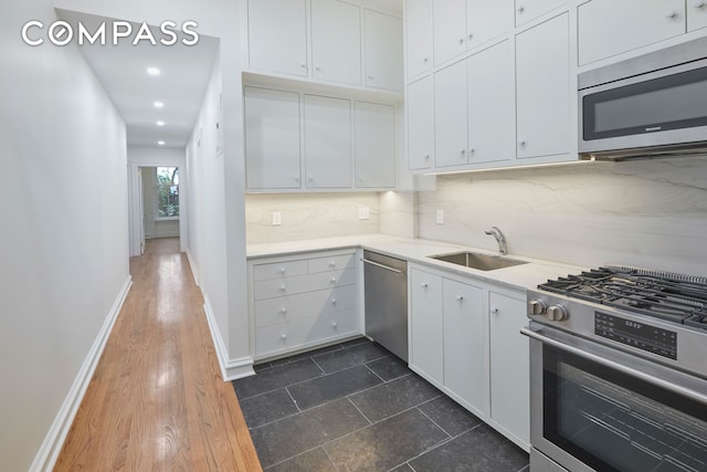 157 E 75th St Unit 1E, New York City, NY 10021 - kitchen featuring appliances with stainless steel finishes, a sink, tasteful backsplash, white cabinets, and recessed lighting