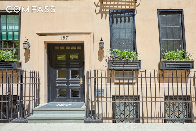 157 E 75th St Unit 1E, New York City, NY 10021 - view of exterior entry with stucco siding and a gate
