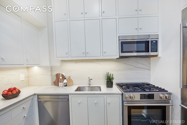 157 E 75th St Unit 1E, New York City, NY 10021 - kitchen featuring appliances with stainless steel finishes, a sink, white cabinets, backsplash, and light stone counters