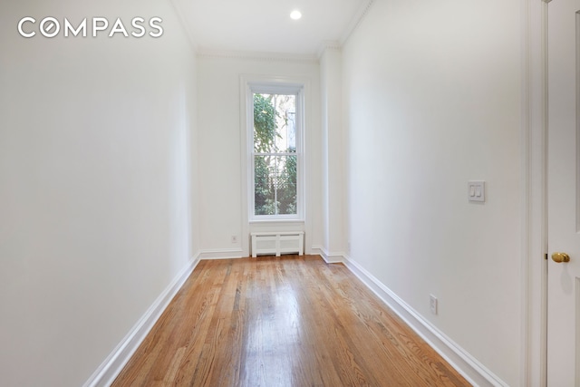 spare room featuring light wood-style floors, ornamental molding, and baseboards