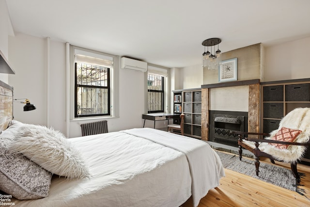 185 12th St, New York City, NY 11215 - bedroom featuring radiator heating unit, an AC wall unit, a fireplace, and wood finished floors