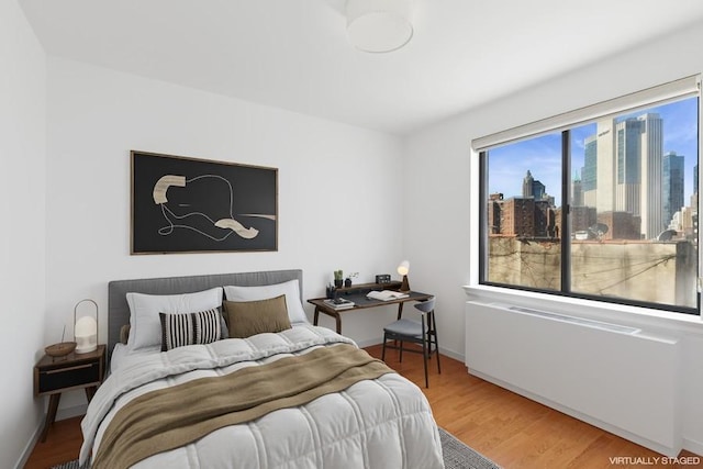 bedroom with a view of skyline, wood finished floors, and baseboards