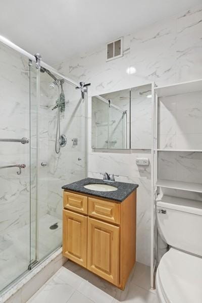 bathroom featuring marble finish floors, a marble finish shower, toilet, and tile walls