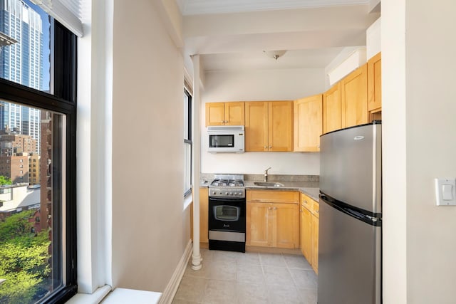 kitchen featuring freestanding refrigerator, white microwave, range with gas cooktop, light brown cabinetry, and a sink