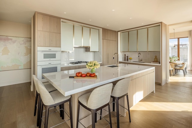 kitchen featuring a sink, stainless steel gas cooktop, double oven, and light wood-style floors
